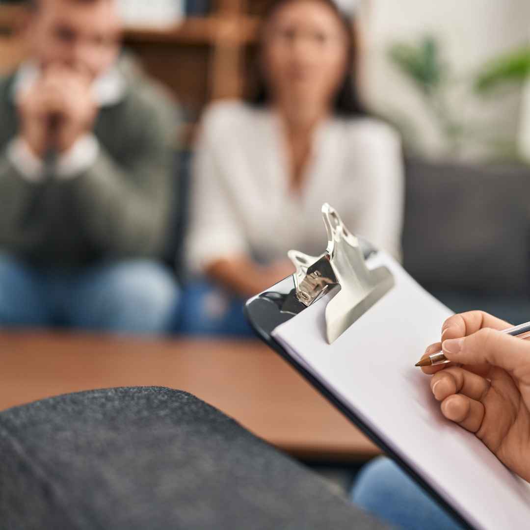 En sexolog i København tager noter under en terapisession for at skabe en dybdegående forståelse af parrets behov.
